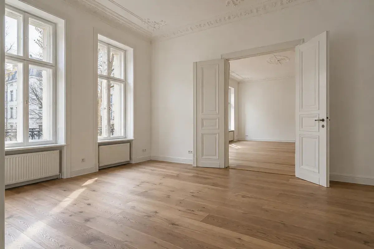 Wohnzimmer einer renovierten Altbauwohnung mit Eichendielen und Stuck